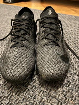 Nike mercurial vapour 16 elite - Säljer ett par svarta Nike fotbollsskor med snyggt mönstrad ovandel och klassisk snörning. Skorna har en låg profil och är tillverkade i syntetmaterial för bra grepp och känsla på planen. Perfekta för dig som vill ha stilrena och funktionella skor till matchen.