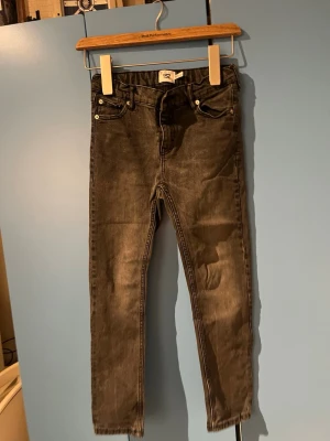 Svarta jeans från 157 - Snygga svarta jeans från 157 med klassisk femficksmodell och raka ben. Jeansen har en tvättad look och silverfärgade detaljer vid fickorna. Perfekta för dig som gillar en enkel och stilren stil.