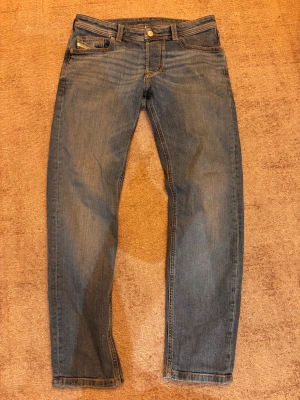 Blå jeans från Diesel Industry - Snygga blå jeans från Diesel Industry med klassisk femficksdesign och läder patch där bak. Jeansen har raka ben, och är tillverkade i slitstarkt denim. Passar dig som gillar en tidlös och cool look. Skick 10/10, storlek 30/30