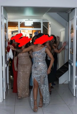 Glittrig silver långklänning med slits - Säljer en maxad långklänning i silver med glittriga paljetter och stenar över hela klänningen. One shoulder-modell med slits framtill och figurnära passform. Klänningen har ett transparent nätlager som ger extra wow-effekt. Perfekt för dig som vill sticka ut! Klänning från Kosovo använd som 3 ombyte  på mitt bröllop hade ungefär på mig den 2 timmar.  Xs/s  Priset kan absolut diskuteras