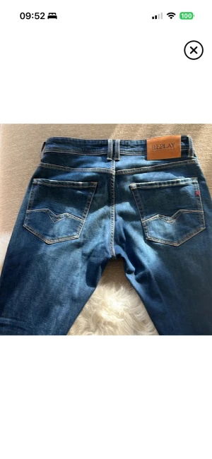 Blå Replay jeans Rocco herr - Snygga blå jeans från Replay, modell Rocco. Klassisk femficksdesign med ljusa slitningar och kontrastsömmar. Skön passform och stilren look, perfekt till sneakers eller boots. Tydlig Replay-lapp bak i midjan och detaljerade bakfickor.