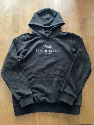 Grå/Svart hoodie från Peak Performance - En grå/svart hoodie från peak performance med en stor ficka fram för barn. Finns ingenting fel med den och passar perfekt till en julklapp eller en present⭐️🎄