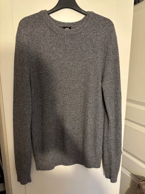 Grå stickad tröja från H&M - En grå stickad tröja från H&M i storlek M. Tröjan har rund halsringning, lång ärm och en grovstickad struktur som ger en chill och stilren vibe. 