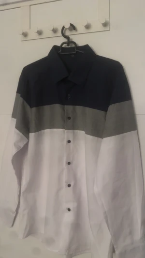 Flerfärgad skjorta med blockmönster - Snygg skjorta med breda block i marinblått, grått och vitt. Klassisk krage, långärmad och knäppning framtill. Perfekt för dig som gillar stilrena färgkombinationer och enkel design.