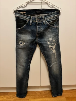 Slim fit jeans Jack & Jones Glenn 29/30 - Snygga slim fit jeans från Jack & Jones, modell Glenn. Mörkblå tvätt med slitningar och läder ficka. 29/30 passar dig runt 180