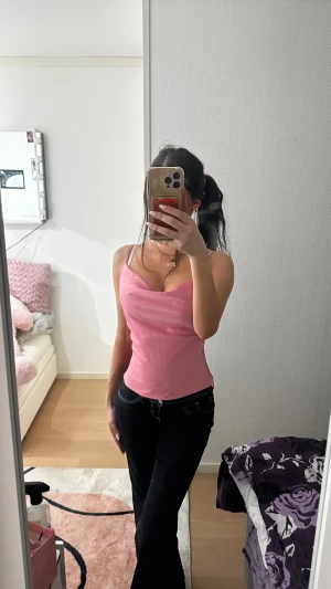 Rosa linnetopp med smala axelband - Säljer en söt rosa linnetopp med smala justerbara axelband och snygg draperad halsringning. Toppen är figurnära och har en mjuk, slät yta som ger en feminin look. Perfekt för dig som gillar stilrena och enkla plagg med lite extra färg.