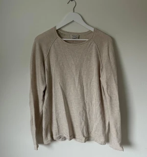 Beige långärmad tröja Selected Homme - Snygg beige långärmad tröja från Selected Homme med rund hals och diskreta sömmar. Tillverkad i mjuk bomull med ekologiska fibrer. Perfekt för dig som gillar enkel och clean stil. Passar dig som vill ha en neutral och chill look. 5K8
