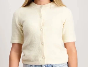 Ljusbeige kortärmad kofta med pärlknappar - Superfin ljusbeige kofta med korta ärmar och rund hals. Koftan är stickad i mjukt material och har pärlknappar framtill som ger en söt touch. Perfekt att styla med jeans eller kjol för en chill och trendig look.