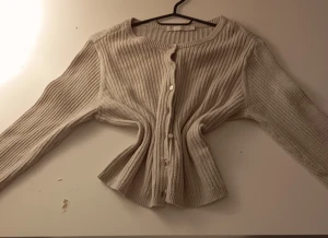 Beige ribbad kofta med knappar - Säljer en beige ribbad kofta med rund hals och långa ärmar. Koftan har knappar framtill och är tillverkad i ett mjukt stickat material som känns skönt mot huden. Perfekt för dig som gillar enkel och clean stil. Det står XL men den har krympt rätt mycket så hade sagt att den är S eller XS