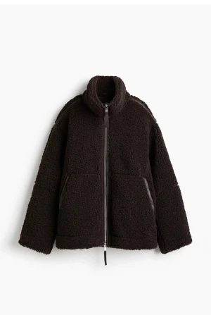 Mörkbrun teddyjacka med dragkedja - Säljer en mörkbrun teddyjacka med hög krage och hel dragkedja framtill. Jackan har två stora fickor och en loose passform som ger en chill vibe. Materialet är mjuk fleece och jackan är perfekt för kalla dagar. Enkel och stilren design som är lätt att matcha. Köpt från H&M.