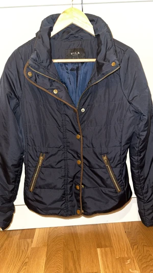 Snygg jacka från Vila blå - storlek S - Marinblå jacka från Vila med dragkedja och knappar framtill. Jackan har två fickor med dragkedja fram.