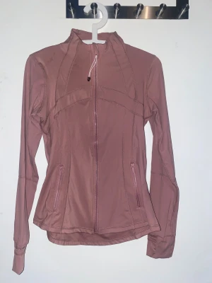 Rosa träningsjacka från Lululemon - Hej💕säljer en rosa/lila define jacket från Lululemon i storlek M. Då jag vart skickad fel färg så är den ej använd och helt ny med tag och påse💕