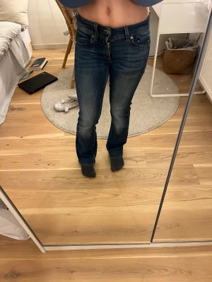 Bootcut lågmidjade jeans - Snygga mörkblå bootcut lågmidjade jeans från G star. Lite slitna på insidan av låret vilket man kan se på bild 4 men det är inget man märker när man har på sig dem!