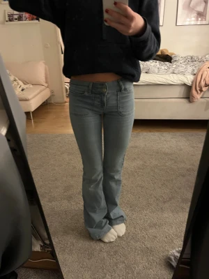 Bootcut jeans i ljusblå denim från Nelly - Bootcut jeans från Nelly i storlek 32. Snygga detaljer med dubbla knappar fram och stora fickor både fram och bak, bakfickorna har lock och knapp. Har blivit lite silorna längs ner på vardera ben. Annars bra skick