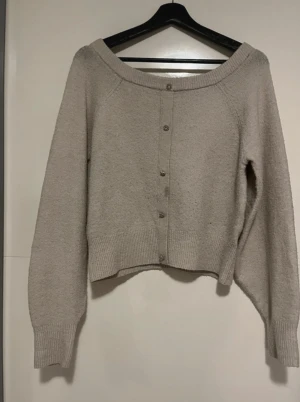 Beige kofta med dekorativa knappar H&M - Säljer en beige stickad kofta från H&M i storlek S. Koftan har långärmade ärmar, bred ribbad kant och snygga dekorativa knappar framtill. Perfekt för dig som gillar en enkel men ändå stylish look. Passar dig som vill ha en neutral färg i garderoben.