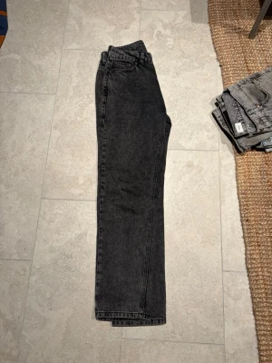 Svarta raka jeans från Grunt - Snygga svarta jeans från Grunt i rak modell. Jeansen är tillverkade i ekologisk bomull och har en klassisk femficksdesign. Perfekta för dig som gillar en clean och enkel stil med en vintagekänsla.