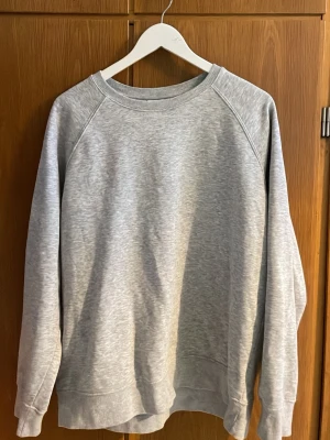 Grå sweatshirt från Weekday - Klassisk grå sweatshirt från Weekday i mjuk bomullsblandning. Tröjan har rund halsringning, ribbade muddar vid ärmslut och nederkant samt en avslappnad passform. Perfekt basplagg för en enkel och clean stil. Ny ej använd inga hål eller smuts 