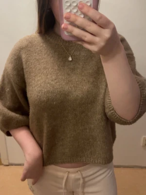 Beige stickad tröja - Säljer en beige stickad tröja med rund hals och halvlånga ärmar. Tröjan har en enkel och stilren design, perfekt att matcha med både jeans och mjukisbyxor. Materialet ser mjukt och bekvämt ut, perfekt för lager på lager.