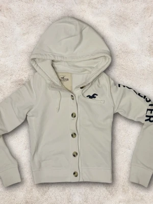 Hollister XS dam - En hollister hoodie storlek XS. Färg vit med mörkblåa detaljer. Mycket bra skick! 😀