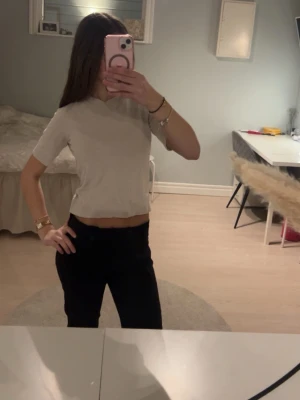 Beige croppad t-shirt - Säljer en beige croppad t-shirt med korta ärmar och rund hals. T-shirten har en enkel och clean look som passar perfekt till jeans eller kjol. Materialet känns mjukt och skönt mot huden, perfekt för dig som gillar en avslappnad men ändå stilren vibe.