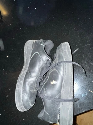 Svarta sneakers från Polo Ralph Lauren - Säljer ett par svarta sneakers från Polo Ralph Lauren med klassisk gul broderad logga på sidan. Skorna har snörning och är tillverkade i skinn med en stilren och enkel design. Perfekta för dig som gillar tidlös streetstyle.