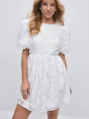 Vit kort klänning med puffärm - Superfin vit kort klänning med puffärmar och blommigt mönster. Superfin öppen rygg också. Endast använd 1 gång på studenten! Strl 36