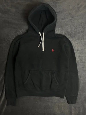 Ralph Lauren hoodie - |Tja! En otroligt snygg och eftertraktad Polo Ralph Lauren hoodie i en skön färg ❗️| Skick 8/10 bra skick, ett pyttelitet hål som lagats vid höger axel☑️| Storlek: M , sitter som M/S, sitter hyfsat bra på mig - 189cm 75kg📏| Nypris: ca 2000kr💵| Färg: svart, som på bilden🖤| Fraktar spårbart via postnord eller instabox📦| Hör av er för mer information!|