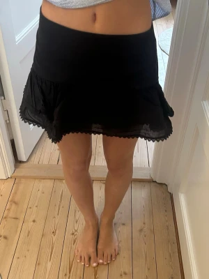 Svart volangkjol med spetskant - Säljer en svart kortkjol med volang och söt spetskant längst ner. Från Zara storlek M