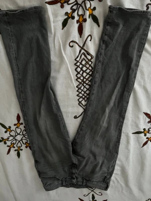 Grå straight regular fit jeans med hög midja - Säljer ett par grå straight regular jeans med hög midja och klassisk femficksdesign som jag har knappt använt. Jeansen har regular passform hela vägen ner och är tillverkade i mjukt jeansmaterial. Perfekta för dig som gillar en clean och enkel look.