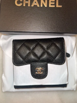 Äkta läder CC plånbok  - Helt ny damplånbok i äkta läder Tillverkad av högkvalitativt äkta läder med mjuk känsla. Logotyp och dragkedja i helt stål – rostar inte och tappar aldrig färg. Mått: 12 cm bred × 27 cm lång. Praktisk och elegant, perfekt för dagligt bruk eller som present. Skicka med sitt original ask. 