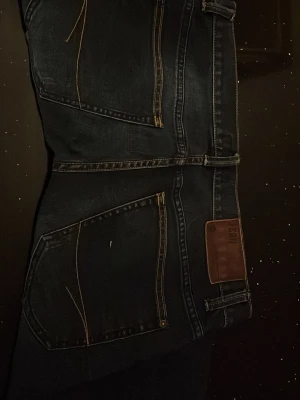 Fsbn 511 mörkblå jeans herr - Snygga mörkblå fsbm 511 jeans med klassisk femficksdesign och brunt läderpatch bak i midjan. Jeansen har raka ben och diskreta kontrastsömmar. Perfekta för dig som gillar en tidlös och clean look.