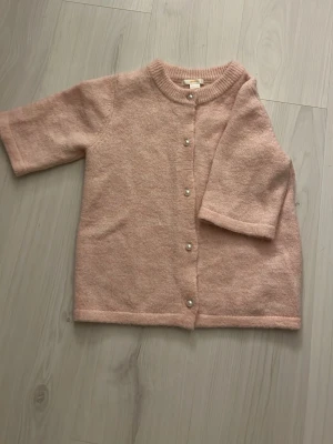 Ljusrosa kofta från Gina Tricot - Jättefin ljusrosa stickad kofta från Gina Tricot med pärlknappar framtill. Koftan har rund halsringning och raka ärmar.