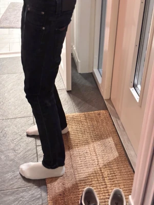 Nudie jeans slim - Säljer ett par mörkblå jeans från nudie med klassisk femficksdesign och smal passform. Jeansen har normal midja och raka ben, perfekta för en stilren look. Materialet är slitstarkt denim i bomull. Snygga och enkla att matcha med det mesta!