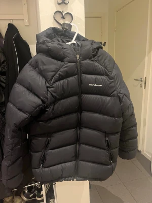 Svart dunjacka Peak Performance - Svart peak jacka, i XL. Men mer M / L. Jackan har en del skador och hål. Även några fläckar. På vänster armen har den förlorat lite dun också. Går att sy igen eller köpa tejp för att täcka igen hålen. Kan skicka fler bilder på den om man vill, så man ser mer exakt vad som är trasigt. Perfekt slit och släng jacka, att ha till att åka pulka, skoter eller vad som helst där man inte behöver vara rädd om jackan. Dragkedjan och allt annat fungerar. 