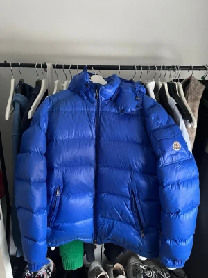 Moncler Maya guibbotto blå - Köpt på NK, kvitto finns! Endast använd och brukad av mig. Använd ca 2 vintrar och är köpt 2022. Resterade av tiden har den hängt i garderob. Storlek 5 och passar mig som är ca 185 och väger 80kg skulle även passa större människor men skulle inte rekommendera mindre människor. Säljer till den som vill ha en seriös deal utan fuffens och garanterad en äkta Moncler jacka i just denna färg. Priset är diskuterbart.