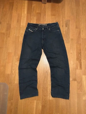 Vintage Diesel Jeans - Vintage Diesel jeans i mörkblå denim med rak passform och fem fickor. Jeansen har knappgylf och tydlig Levi's-lapp bak i midjan. Perfekta för dig som gillar en tidlös och avslappnad stil. Super bra kvalitet. 