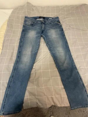 Blå Replay jeans med raka ben - Snygga blå jeans från Replay med klassisk tvätt och raka ben. Jeansen har fem fickor, diskreta slitningar och logga på bakfickan. Perfekta för en avslappnad och trendig look. Säljer dom pågrund att dom var förstora för mig ny pris 950