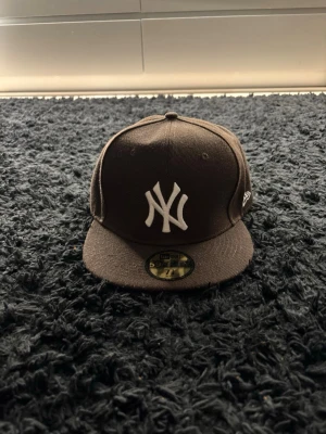 New Era NY Yankees svart keps - Svart New Era 59FIFTY keps med klassisk New York Yankees-logga broderad i vitt framtill. Kepsen har rak skärm och broderad New Era-logga på sidan. Perfekt för dig som gillar streetwear och sportig stil.
