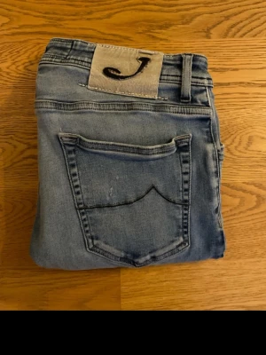 Ljusblå jeansbyxor Style 622 - Säljer ett par ljusblå jeansbyxor från Jacob Cohen i modellen 622. Storlek W33, bredd 42 cm, längd 88 cm