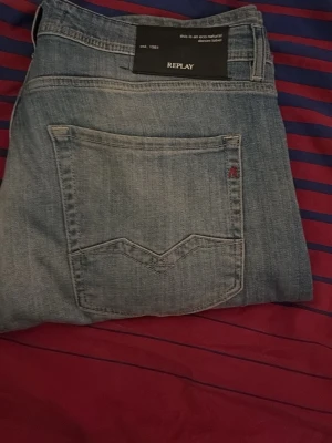 Replay ljusblå jeans straight fit - Snygga ljusblå jeans från Replay med klassisk femficksdesign och raka ben. Jeansen har diskreta slitningar och en stilren bakficka med Replay-logga. Perfekta för dig som gillar en enkel och tidlös look. W32 L34 knappt använda!