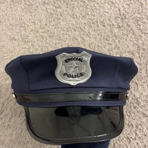 Poliskeps med silvermärke - Mörkblå keps i klassisk polismodell med blank svart skärm och ett stort silverfärgat märke framtill där det står 'Special Police'. Perfekt för maskerad eller temafest. Perfekt till halloween❤️