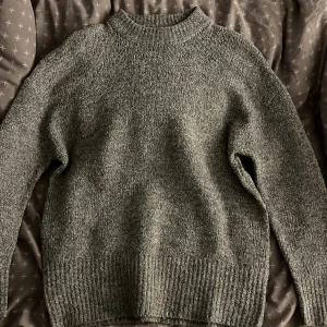 Grå stickad tröja från 157  - Mysig grå stickad tröja från lager 157 i storlek XS. Tröjan har en klassisk rund halsringning, ribbade muddar och är tillverkad i en mjuk blandning av polyester, akryl och elastan. Perfekt för lager-på-lager under kyliga dagar.