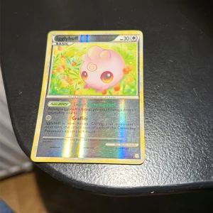 Igglybuff - Upptäck den söta och glittriga Igglybuff Pokémon-kortet! Perfekt för samlare och fans som vill ha något unikt i sin samling. Kortet har holografisk effekt och färgglad design som gör det extra coolt för unga Pokémon-entusiaster.