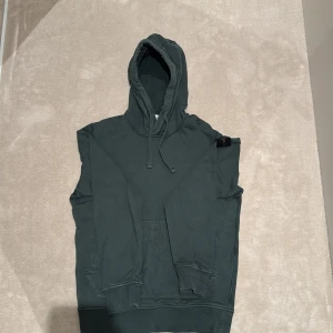 Mörkgrön hoodie från Stone Island - Säljer en mörkgrön hoodie från Stone Island med klassisk logotyp på ärmen. Tröjan har huva med snörning, magficka och ribbade muddar. Materialet är mjuk bomull den är i bra skick och är i strl S.