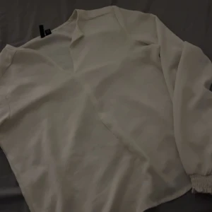 Vit blus från Vero Moda XS - Säljer en stilren vit blus från Vero Moda i storlek XS. Blusen har v-ringning, långa ärmar med resår vid ärmslut och är tillverkad i ett mjukt, lätt material. Perfekt att matcha med jeans eller kjol för en fräsch look.