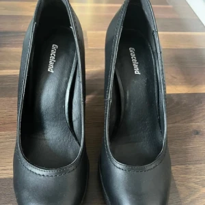 Svarta pumps från Graceland, storlek 38 - Snygga svarta pumps från Graceland i storlek 38. Skorna har hög klack och plattformsula för extra komfort. Tillverkade i syntetmaterial med rund tå och stilren design som passar till många outfits.