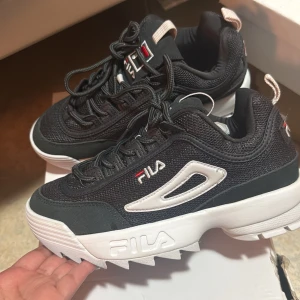 Fila Disruptor Mesh Low sneakers gråa - Säljer ett par Fila Disruptor Mesh Low sneakers i svart med vita detaljer och chunky vit sula. Skorna har mesh-överdel, snörning och Fila-logga på sidan och sulan. Riktigt snygga och trendiga med grov plattformssula och sportig vibe.
