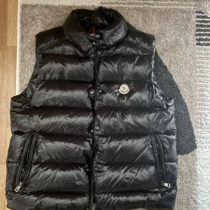 Svart dunväst från Moncler - Svart dunväst från Moncler, Storlek 5 enligt etikett, men sitter mer som M/L. Klassisk Moncler-passform, ganska slim. Den är i väldigt bra skick.