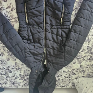 Svart quiltad pufferjacka H&M XS - Svart pufferjacka från H&M i storlek XS. Jackan har quiltad design, huva och dragkedjor i silverfärg. 