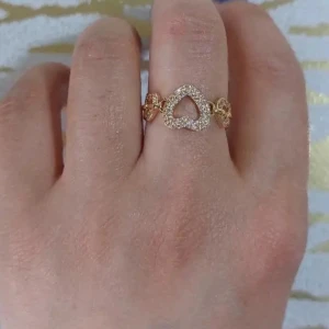 Guldfärgad ring med hjärtan och strass - Superfin guldfärgad ring med glittrande strass och hjärtformad design. Ringen har flera små hjärtan runt bandet och ett större hjärta i mitten som är täckt av små stenar. Perfekt för dig som gillar söta detaljer och bling.